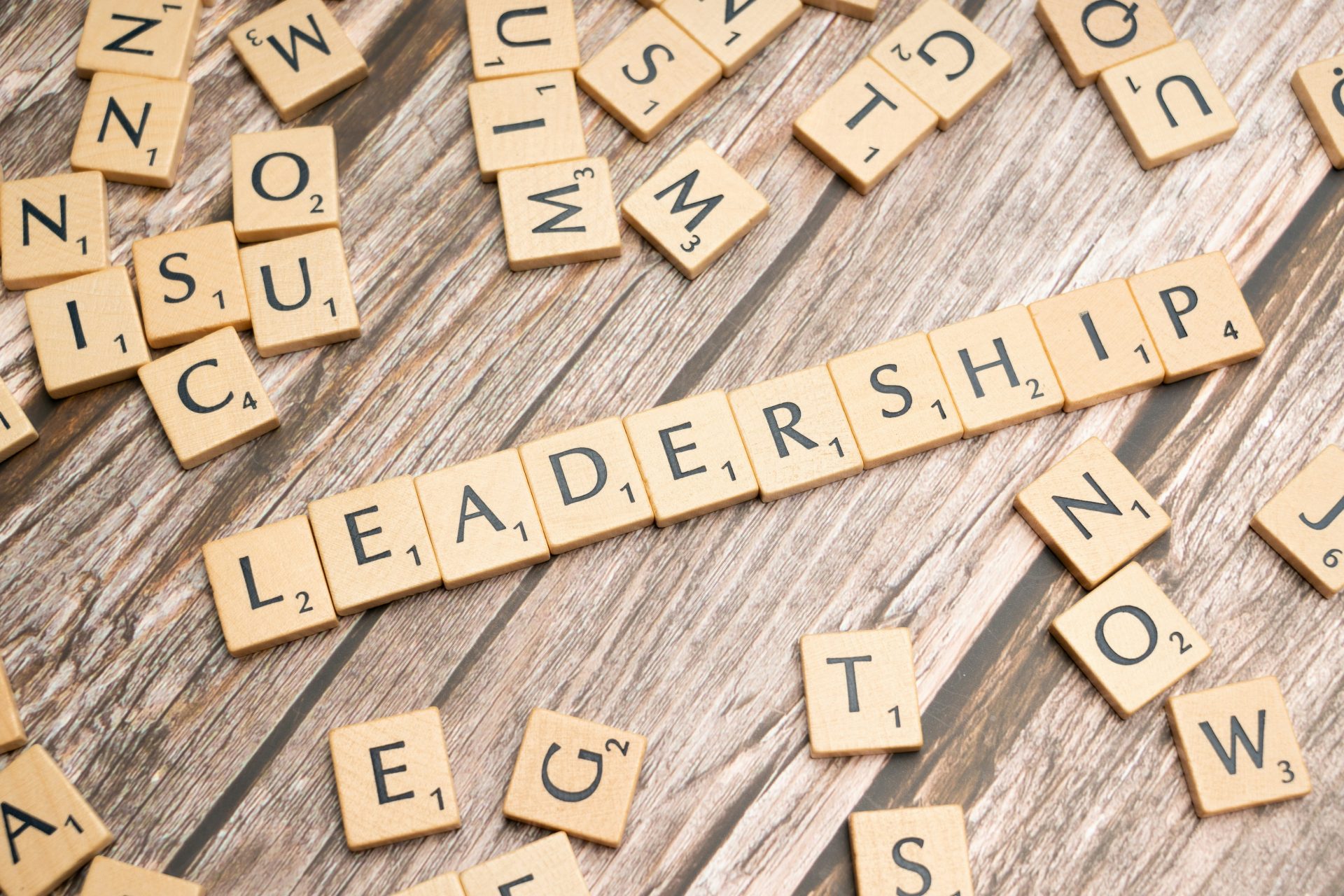 Mot “leadership” formé avec des lettres de Scrabble sur un fond en bois, illustrant la construction et la réflexion du leadership émotionnel.